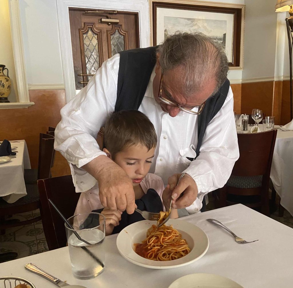 Elder man teaching a child how to twirl spaguettis